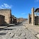 Ancient stone street lined with ruins of buildings in the archaeological site of Pompeii